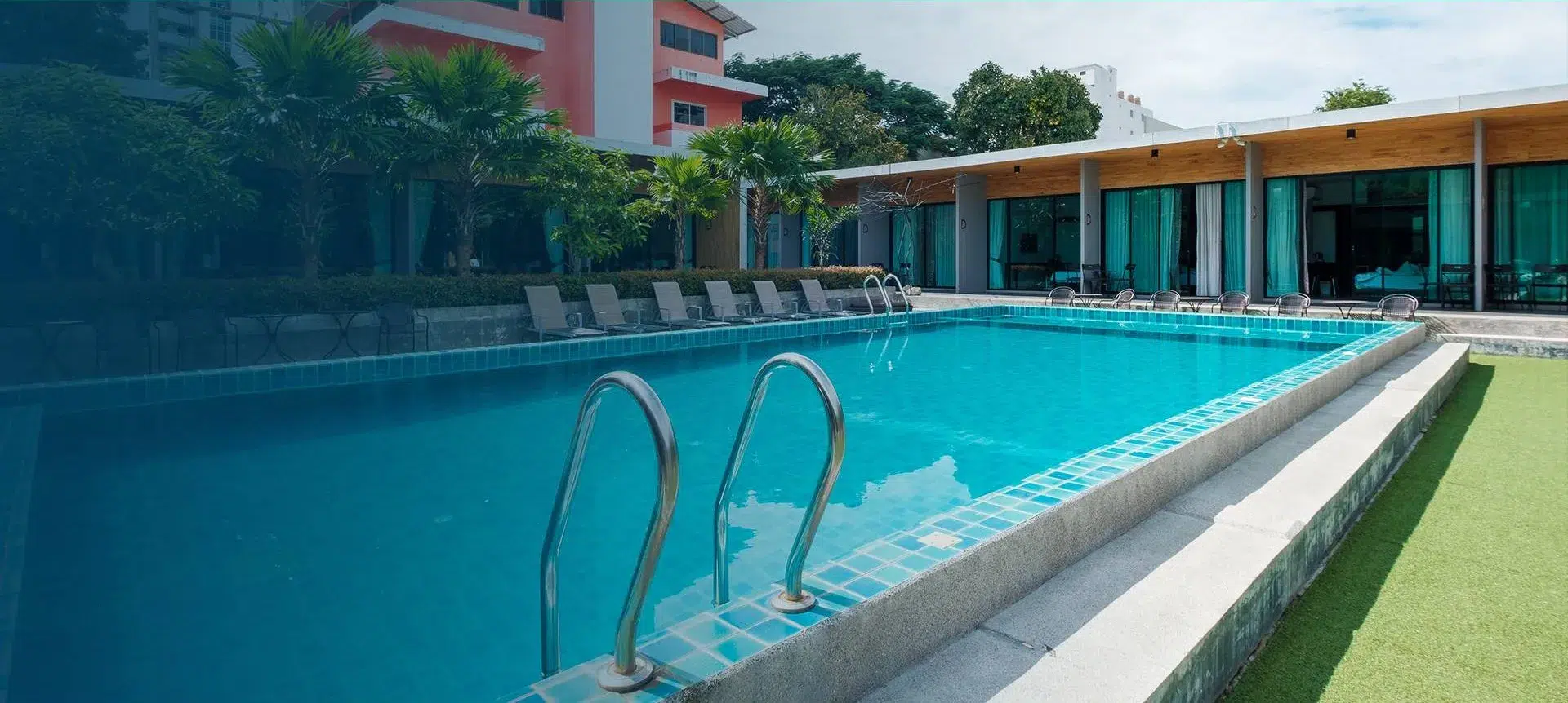 Coiled green hose and blue toolbox with safety helmets next to a swimming pool during resurfacing work.