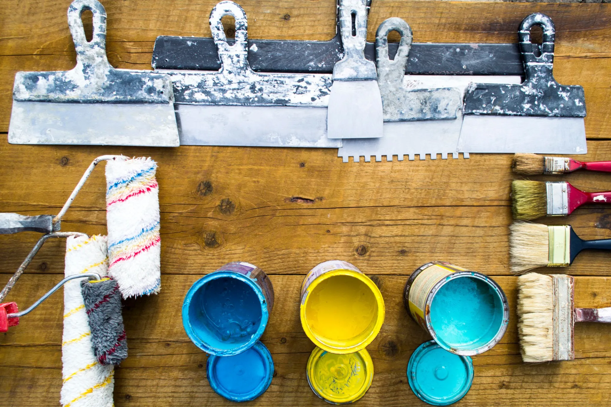 DIY pool painting supplies laid out including brushes, rollers, paint, and safety equipment