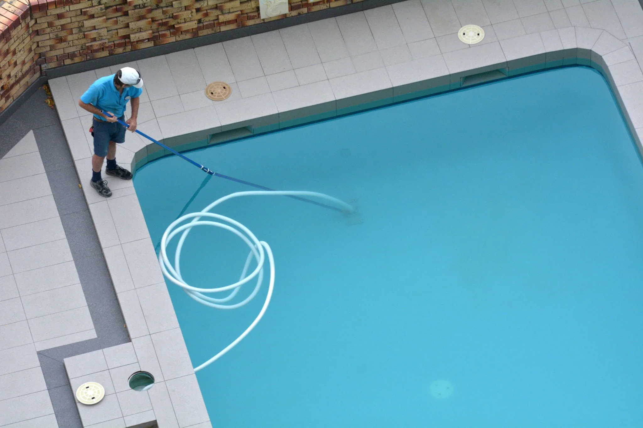 Professional pool painters working on a Sydney pool with proper equipment and safety gear
