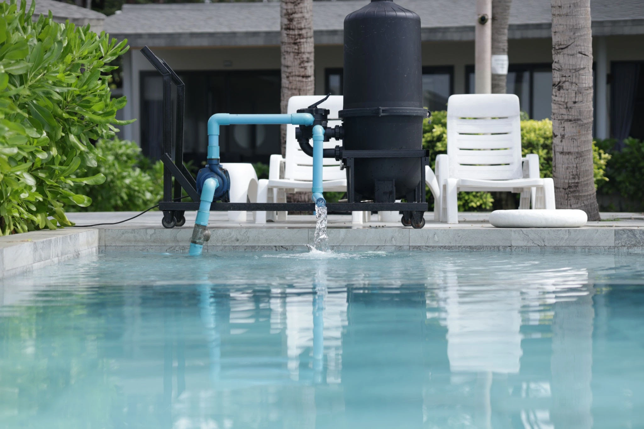 Close-up of modern salt chlorine generator installed on pool equipment pad, showing digital display and cell housing